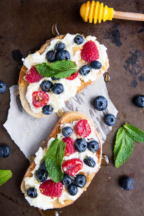 Generous smears of creamy ricotta cheese are paired with blueberries, raspberries, drizzled with lots of honey and tangy mint. A spring breakfast.