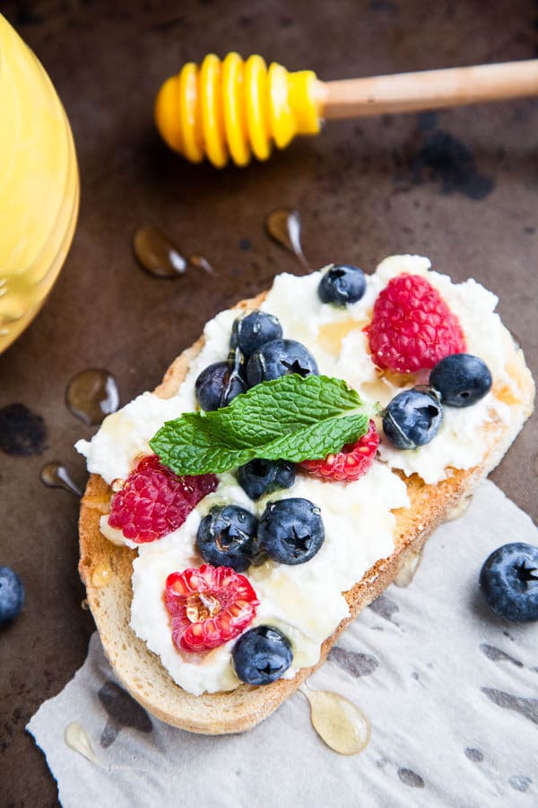 Generous smears of creamy ricotta cheese are paired with blueberries, raspberries, drizzled with lots of honey and tangy mint. A spring breakfast.