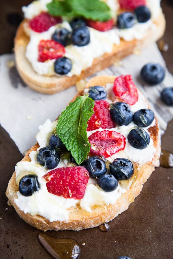 Generous smears of creamy ricotta cheese are paired with blueberries, raspberries, drizzled with lots of honey and tangy mint. A spring breakfast.