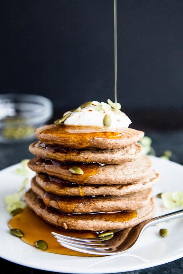 Stack of oat flour blender pancakes with syrup drizzle on a white plate.