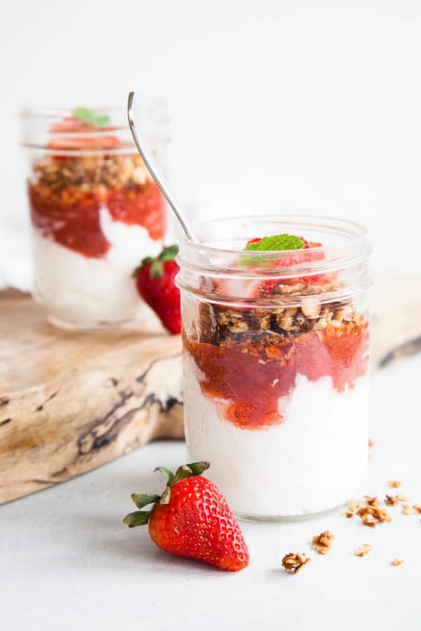 Breakfast parfaits with homemade strawberry rhubarb compote layered with Greek yogurt and granola. Recipe yields up to 6 half-pint mason jar servings - perfect for meal prepping!