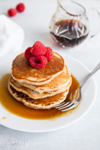 Stack of whole wheat pancakes with syrup.